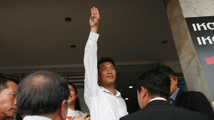 Thanathorn Juangroongruangkit holds his arm straight in the air in a three-finger salute popularised by The Hunger Games