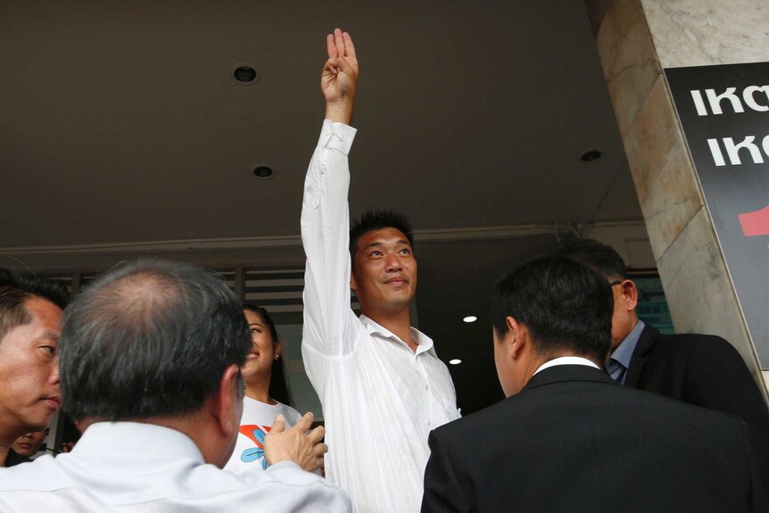 Thanathorn Juangroongruangkit holds his arm straight in the air in a three-finger salute popularised by The Hunger Games