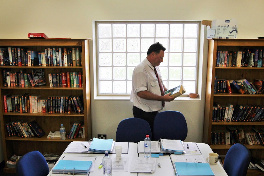 Education Coordinator Peter Fox returns books to the Mount Gambier Prison library bookshelves.