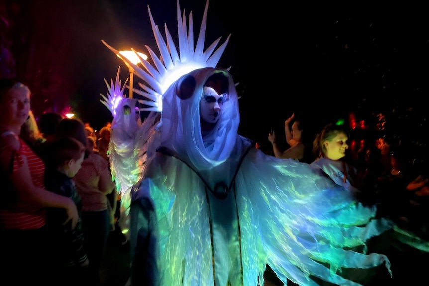 A lit up performer in a crowd