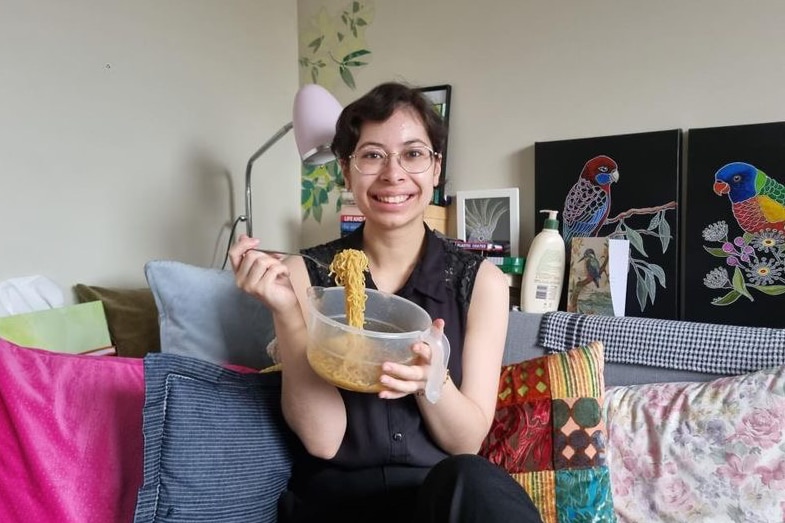 A young woman holding a plate of instant noodles.