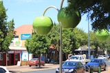 Street lights in the shape of large apples hang over a town's main street