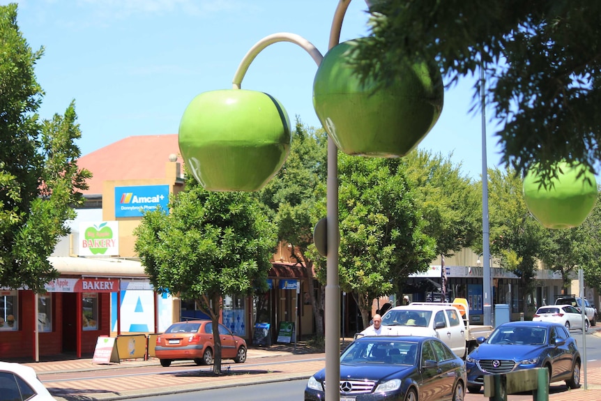 Street lights in the shape of large apples hang over a town's main street