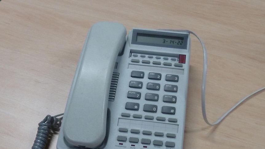 White/beige ordinary phone sits on desk clear of any clutter