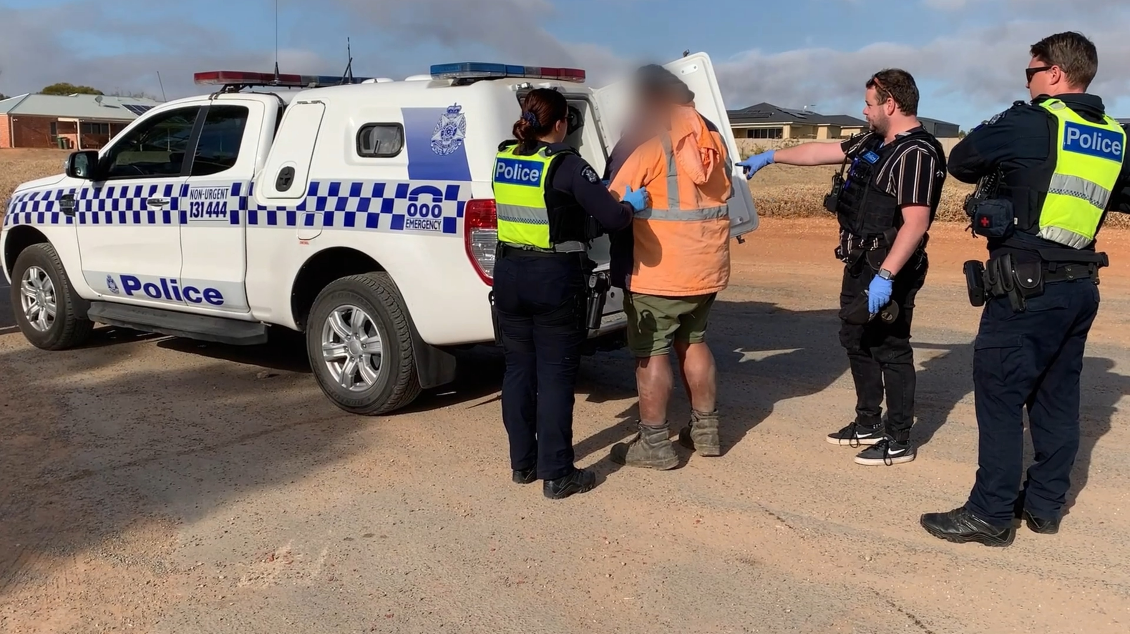 A man in a high-visibility jacket is arrested by Victoria Police