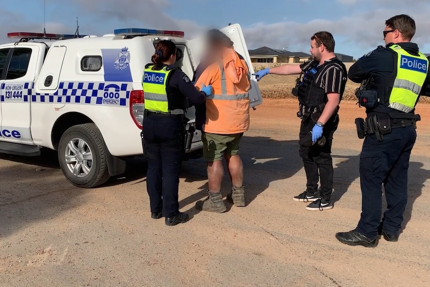 A man in a high-visibility jacket is arrested by Victoria Police
