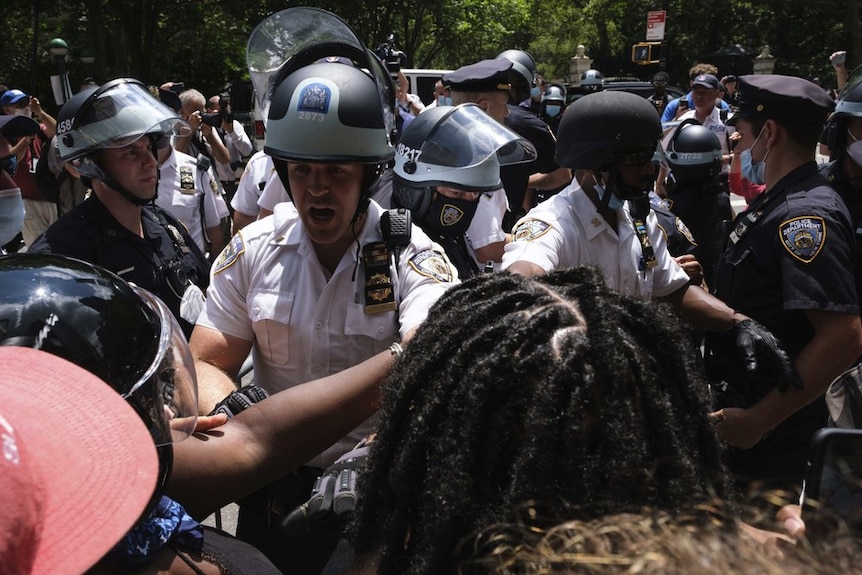 Police engage with protesters. One officer has a small black band covering the insignia of his badge.