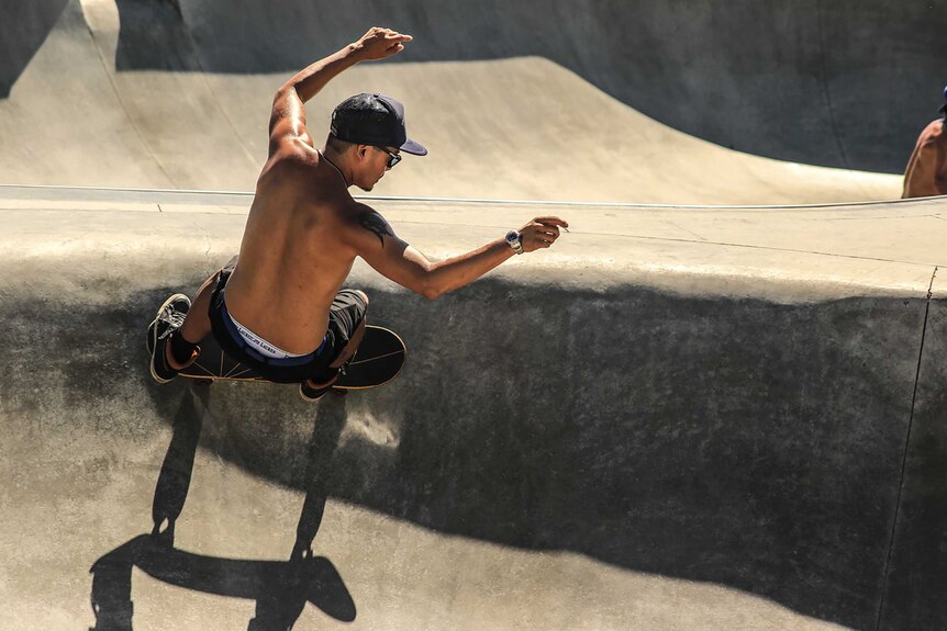Shirtless person skateboarding in a skate bowl