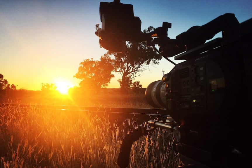 Camera on train tracks filming sunset.