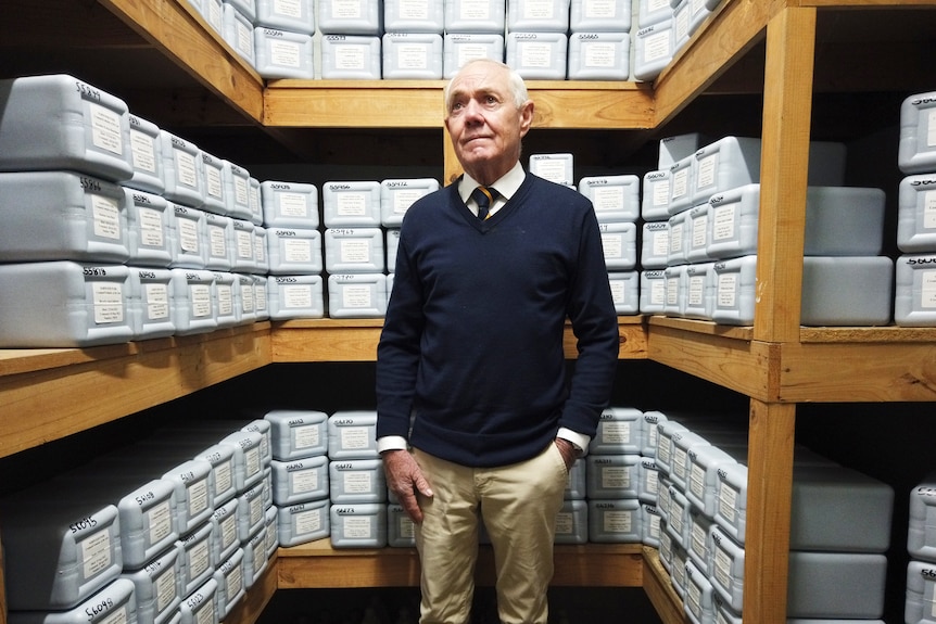 A man standing in front of shelves of cremations in boxes.