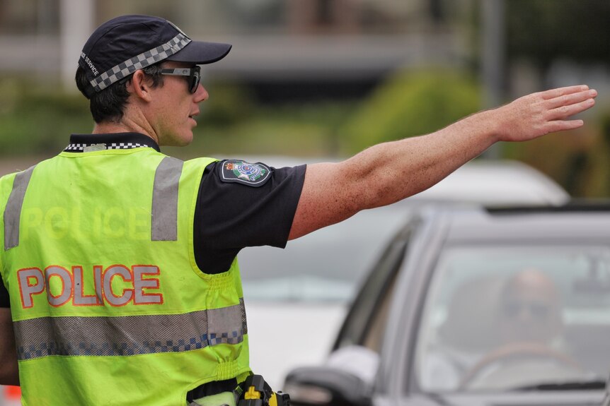 Queensland police officer in high-vis directs traffic at a border checkpoint at Coolangatta.