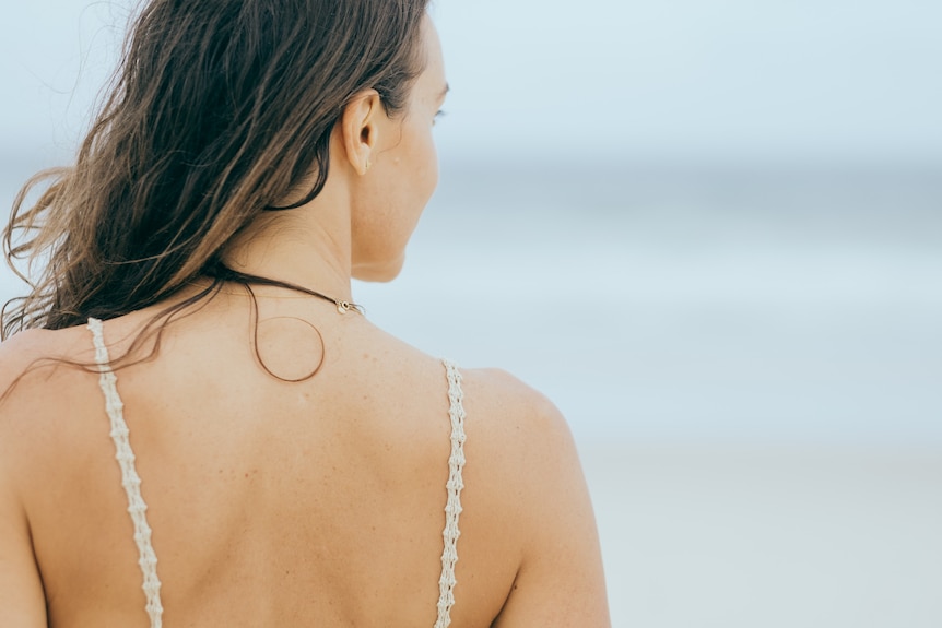 The back of the head and shoulder of a woman at the beach. 