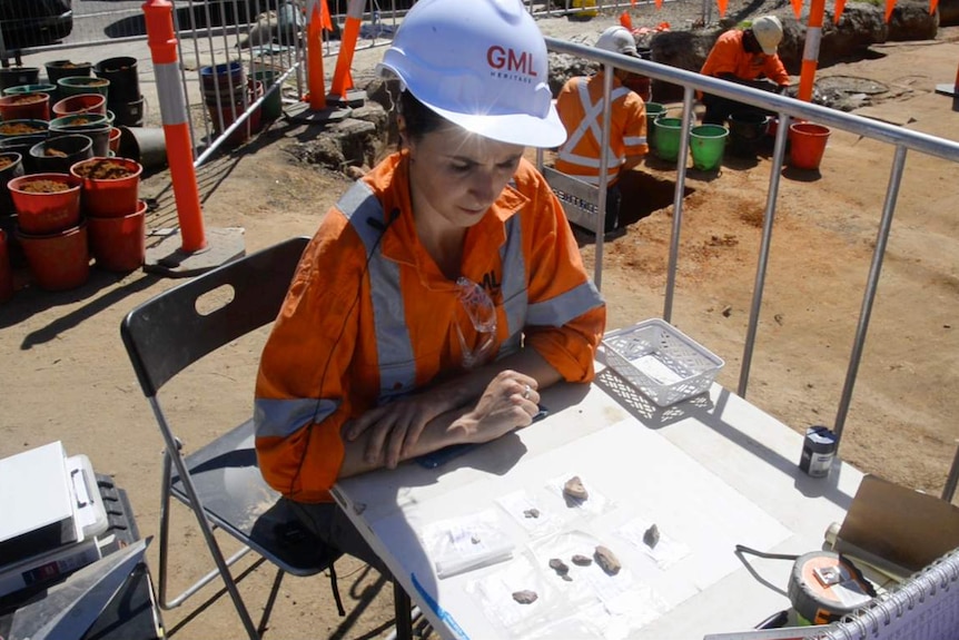 An archaeologist looks at stone collections from a heritage dig