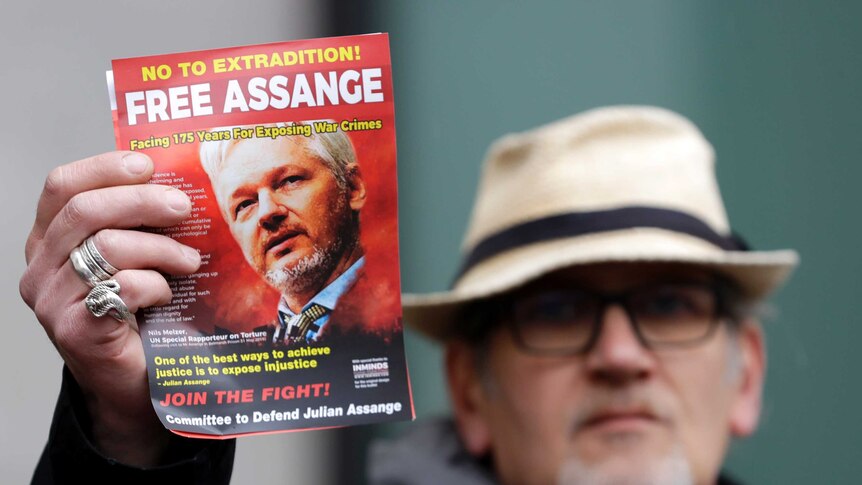 A pro-Assange demonstrator holds a leaflet outside Westminster Magistrates Court in London.