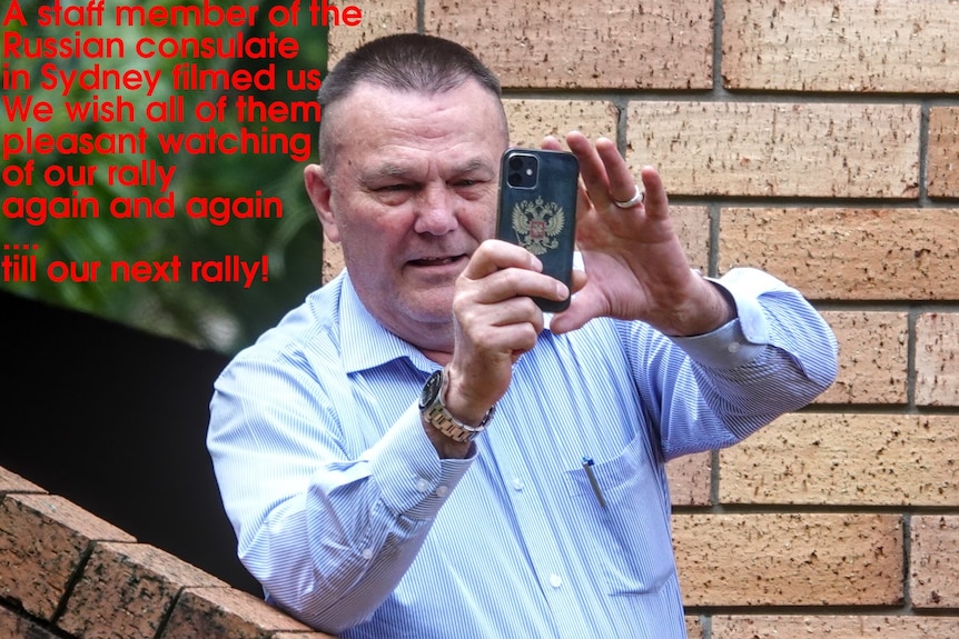 A man holds his phone up to film, a Russian double-headed eagle on the phone, a caption wishes him "pleasant watching"