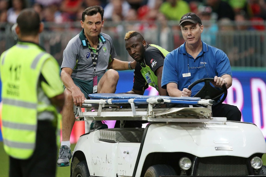 Injured Sydney Thunder player Andre Russell is driven off in the BBL match against Melbourne Stars.