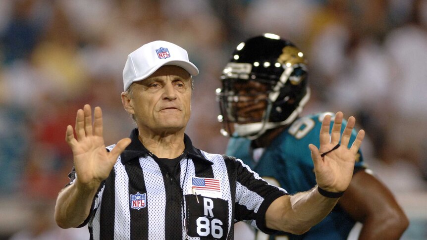 NFL referee signals a pass interference penalty.