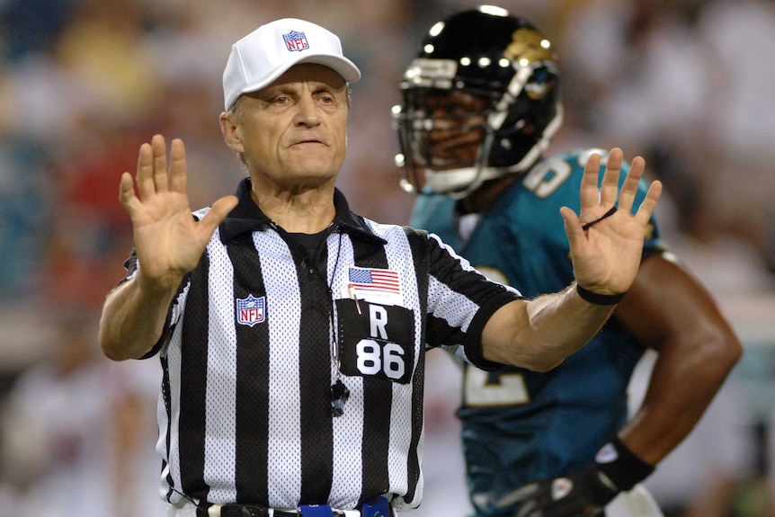NFL referee signals a pass interference penalty.