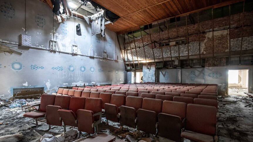 Light shines through a large hole in the roof of an abandoned theatre.