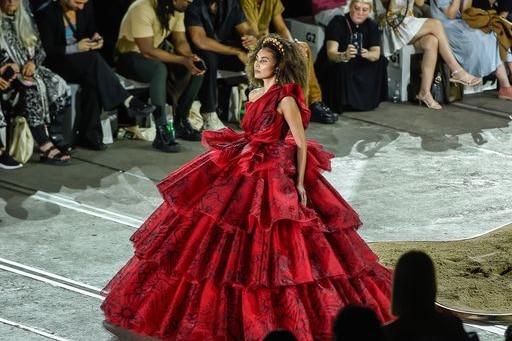 A woman in a beautiful red dress with ruffles and ruffles to the floor.