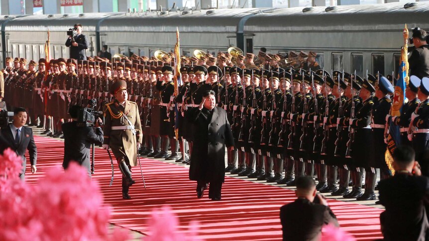 Kim Jong-un walks past military personnel in Pyongyang on his way to the summit in Hanoi