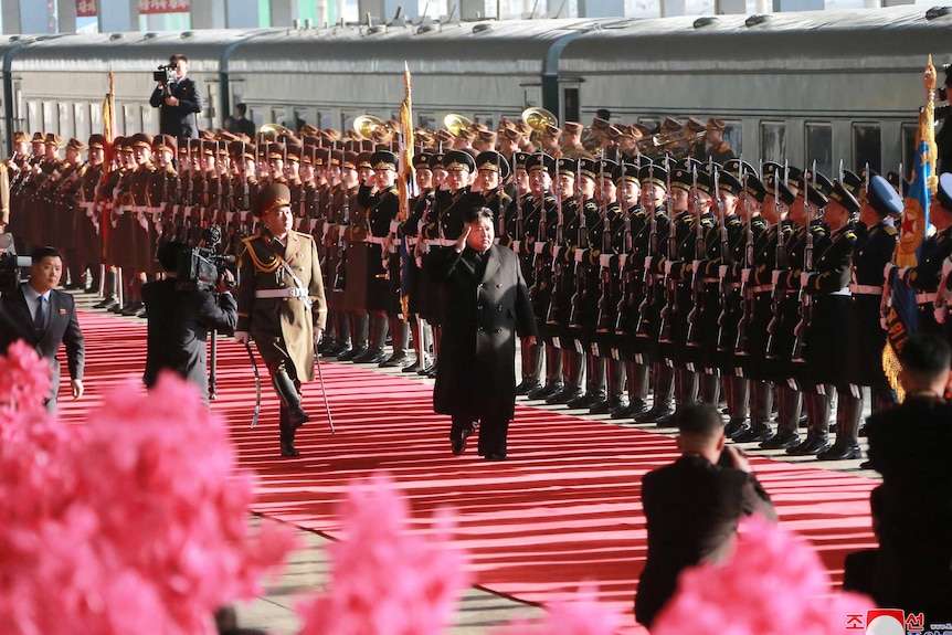 Kim Jong-un walks past military personnel in Pyongyang on his way to the summit in Hanoi