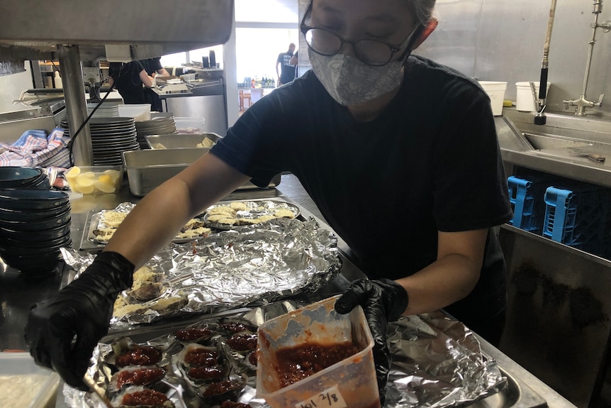 Employee preparing takeaway oysters