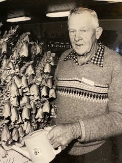 black and white picture of man holding watering can and watering flowers