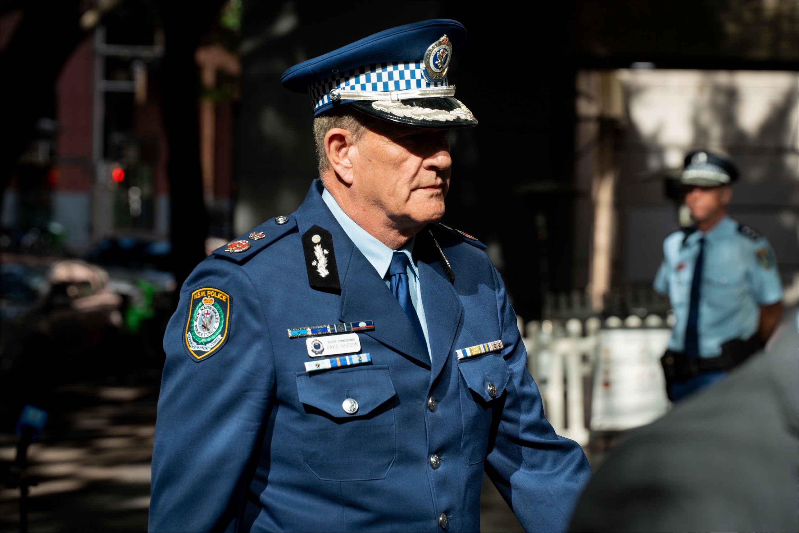 Deputy commissioner Hudson in his police uniform walking into a building.