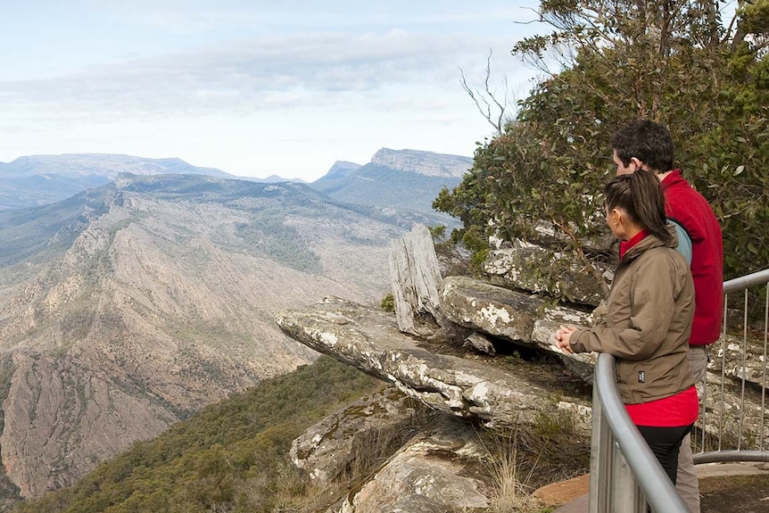 Two people stand behind a barrier at a lookout in the Grampians National Park.