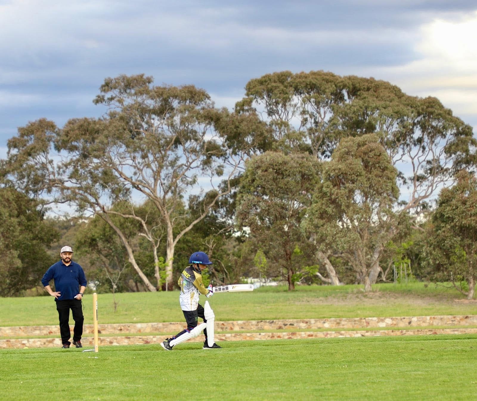 Pessoas jogando críquete no campo.