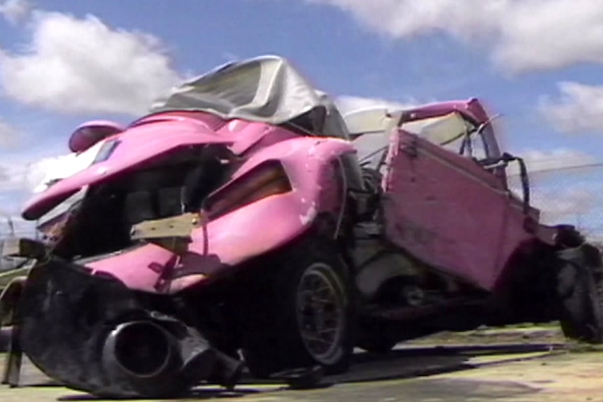The mangled wreck of a pink Volkswagen Beetle