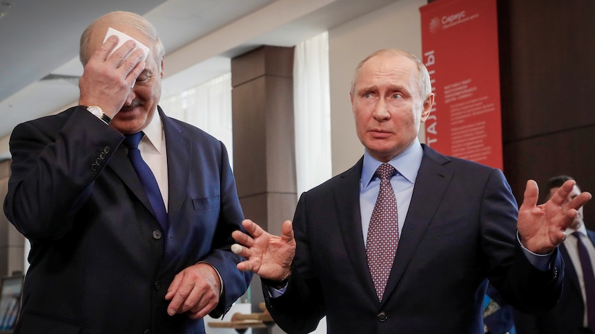 Vladimir Putin gesticulates as Alexander Lukashenko uses a hanky to mop his brow
