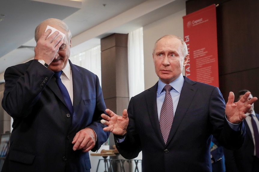 Vladimir Putin gesticulates as Alexander Lukashenko uses a hanky to mop his brow
