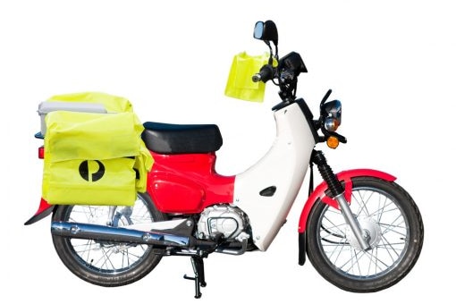A two wheeled red bike with yellow bag with Australia Post logo on the back and long, low exhaust bike