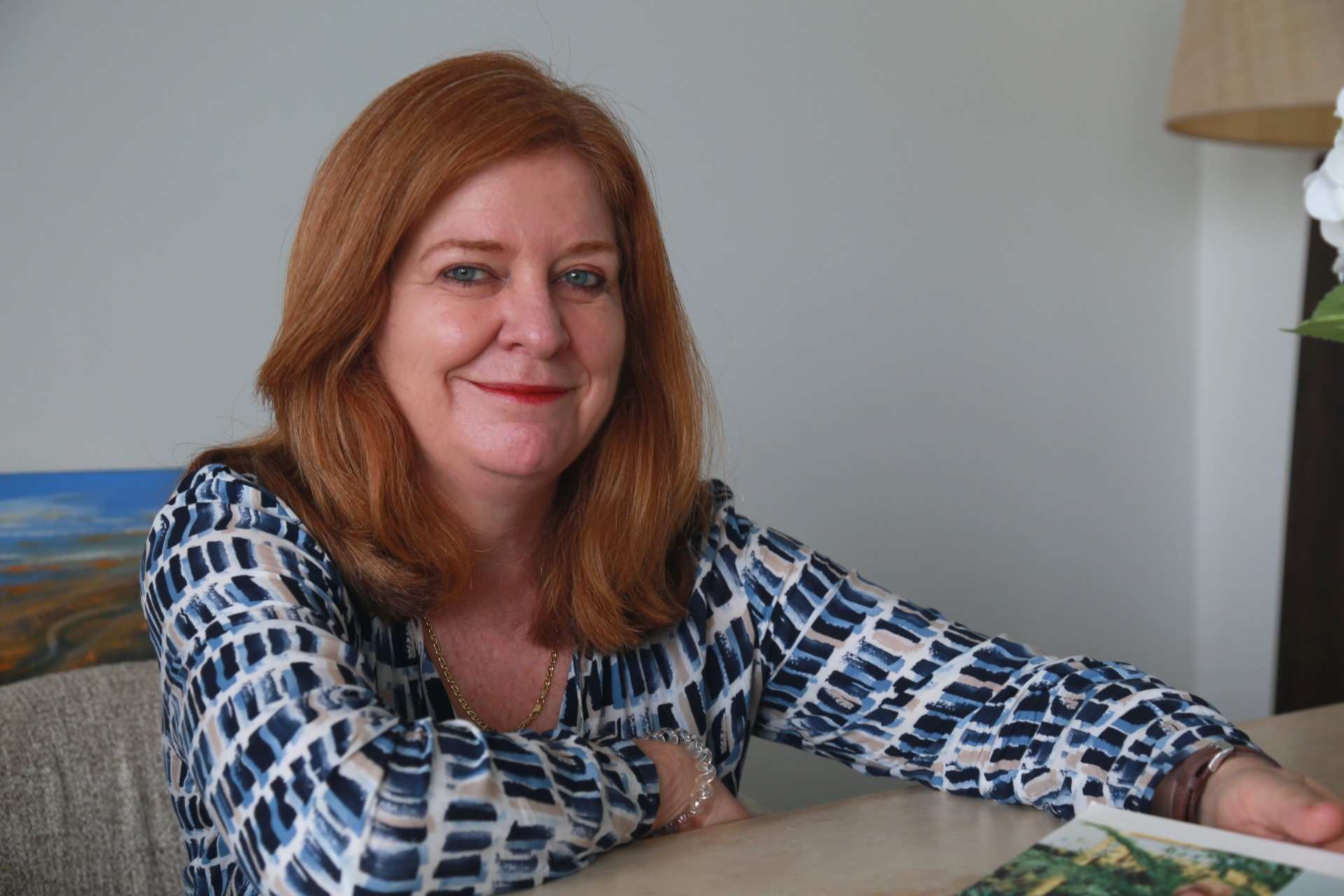 Portrait of a woman with red hair and light blue eyes.