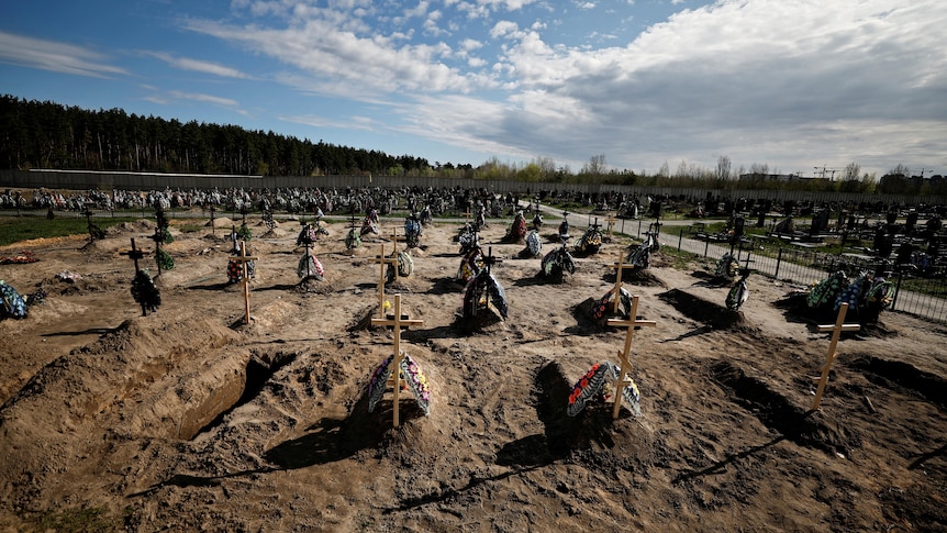 A row of graves is seen bug in the dirt with simple wooden crosses.