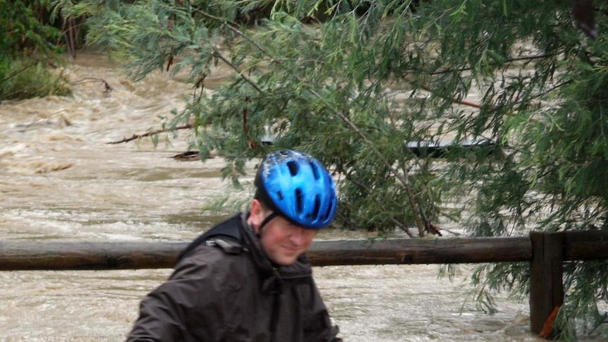 A man pushes his bike through floodwaters from Mullum Mullum Creek