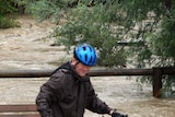 A man pushes his bike through floodwaters from Mullum Mullum Creek