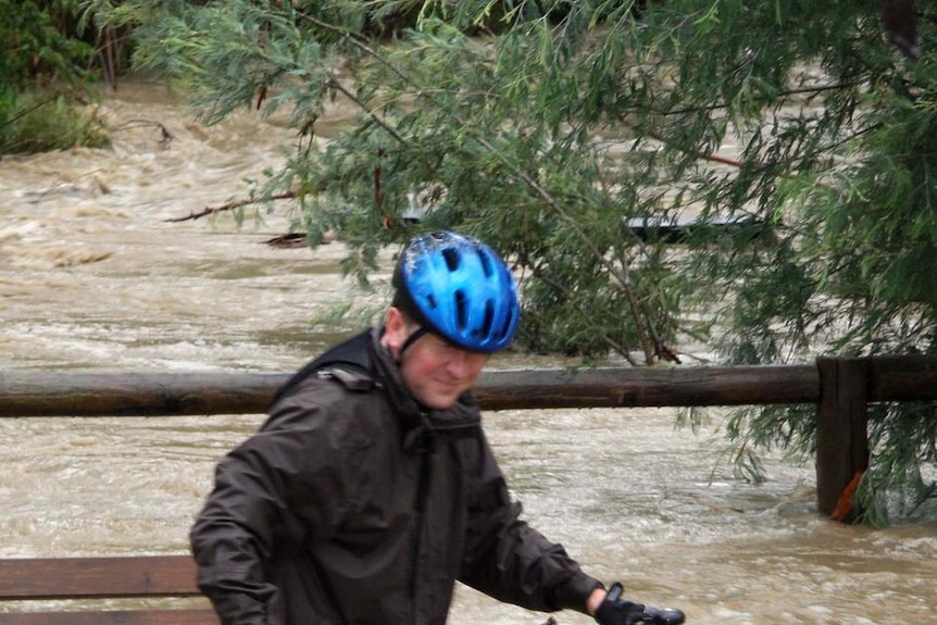 A man pushes his bike through floodwaters from Mullum Mullum Creek