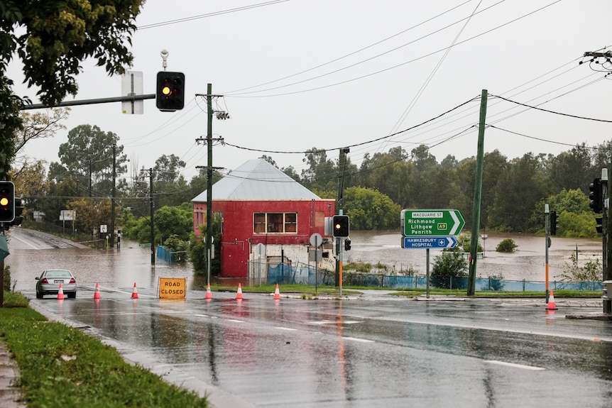 A road is closed next to a flooded river,