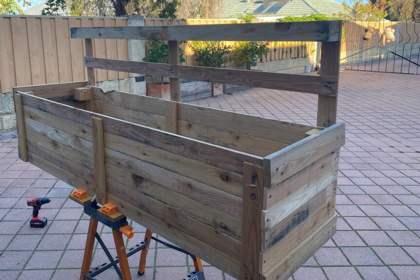 A wooden planter box made using pieces from an old pallet.