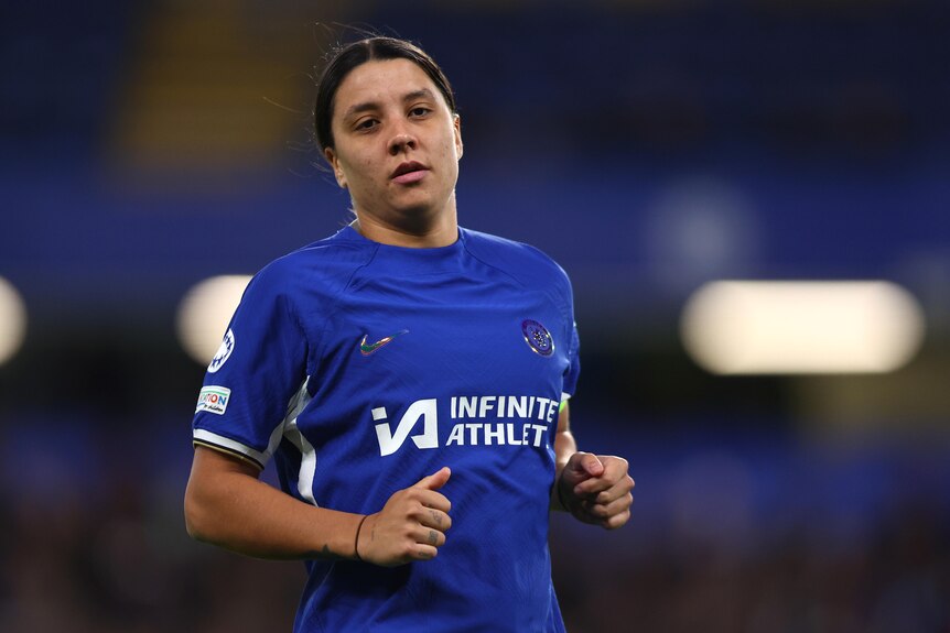 Chelsea's Sam Kerr looks serious as she stands on a pitch during a game. 