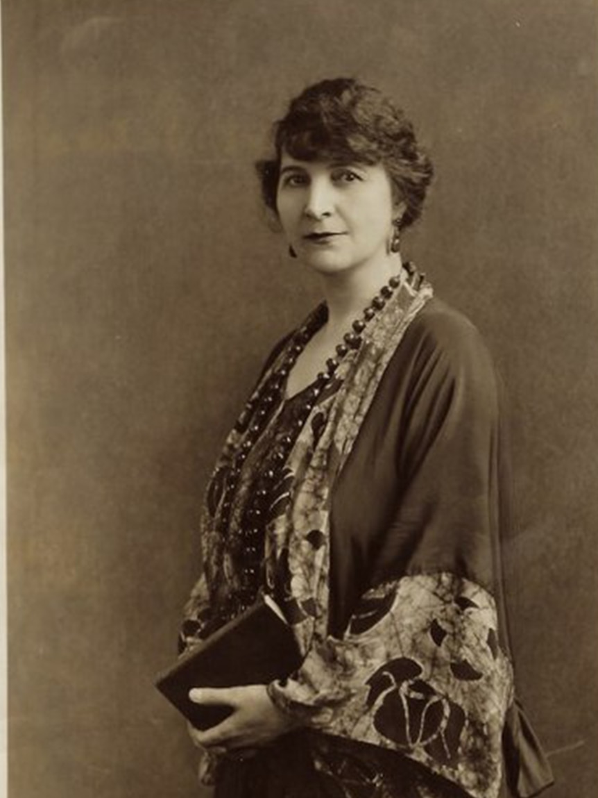 Black and white photo of a short-haired woman holding a book. 