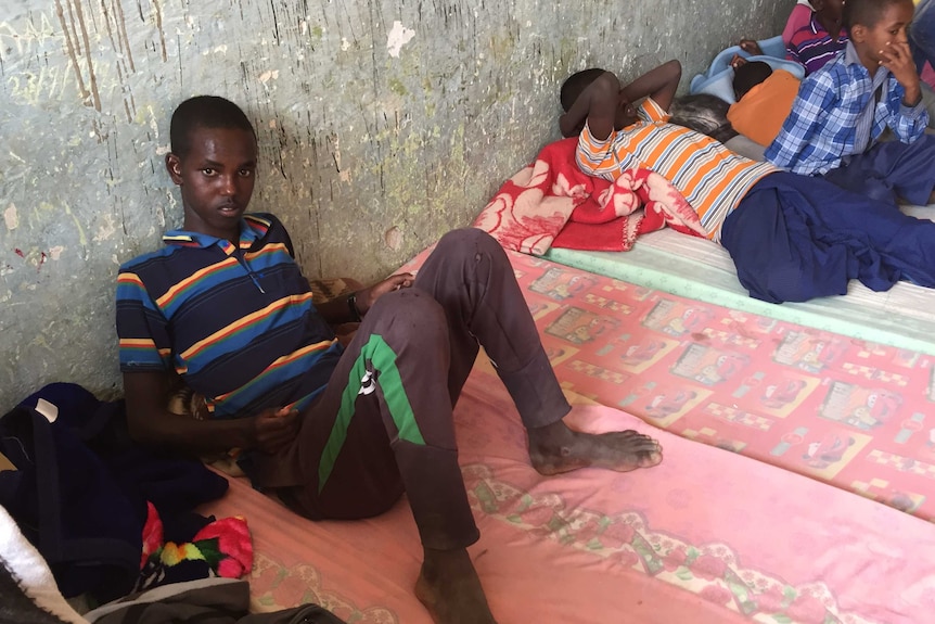 Boy sits on mattress inside school