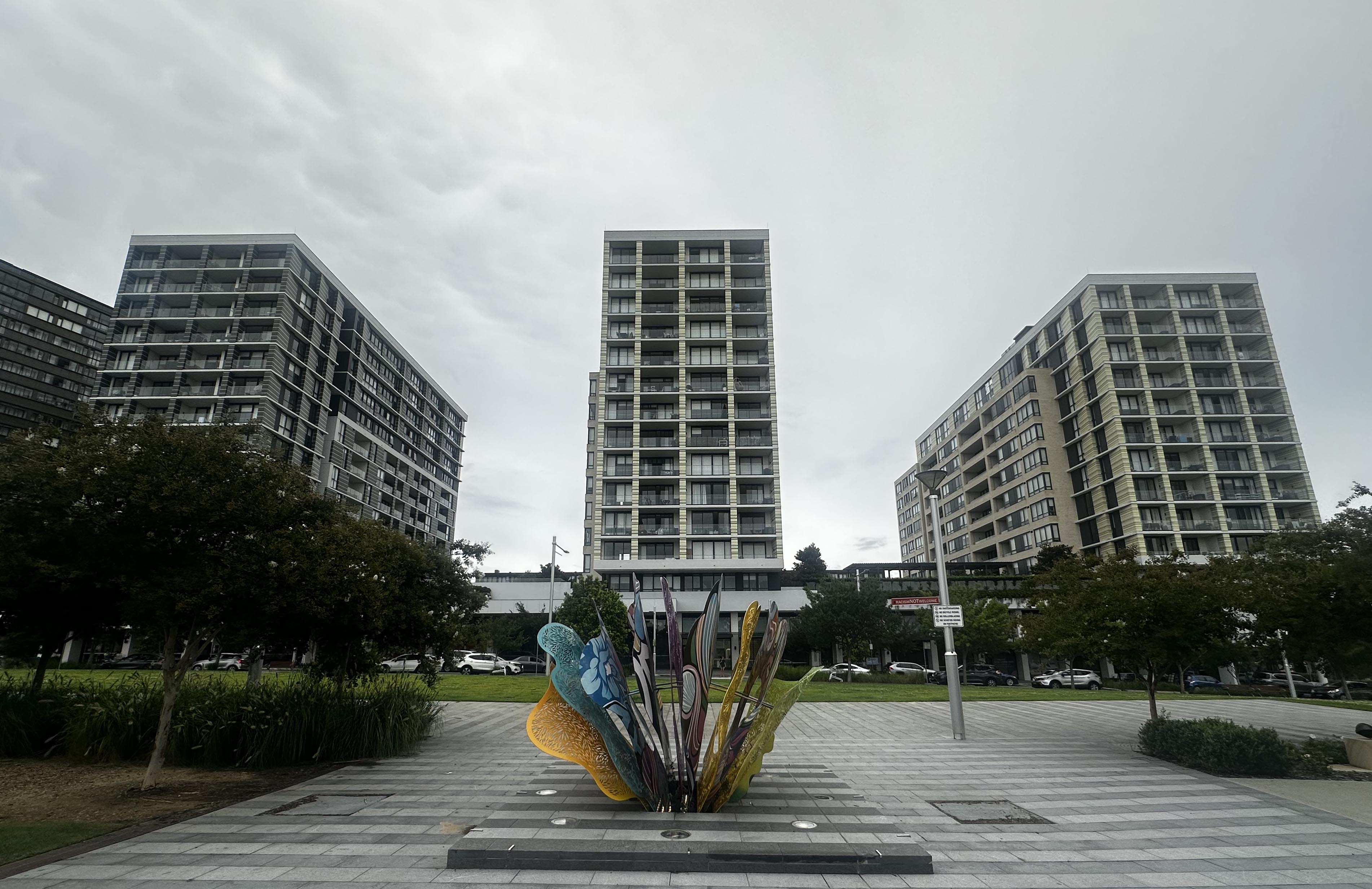 Three buildings visible with a colourful statue in front