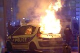 A large fire consumes a French police car during protests.