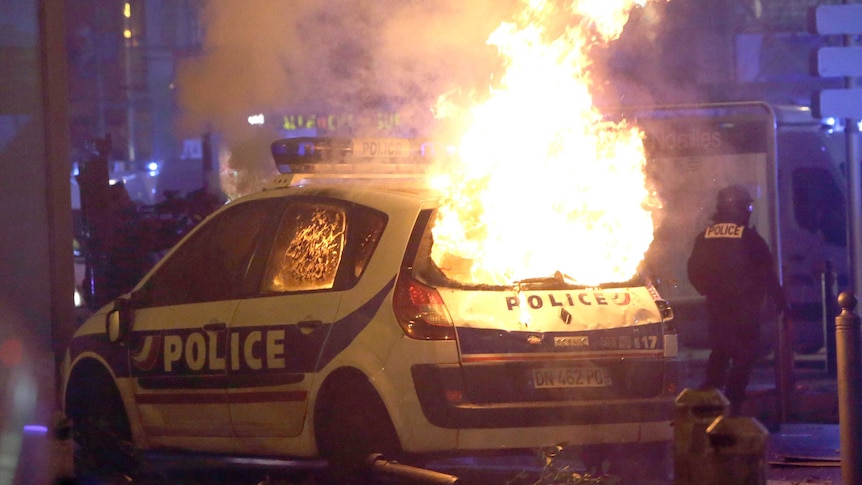 A large fire consumes a French police car during protests.