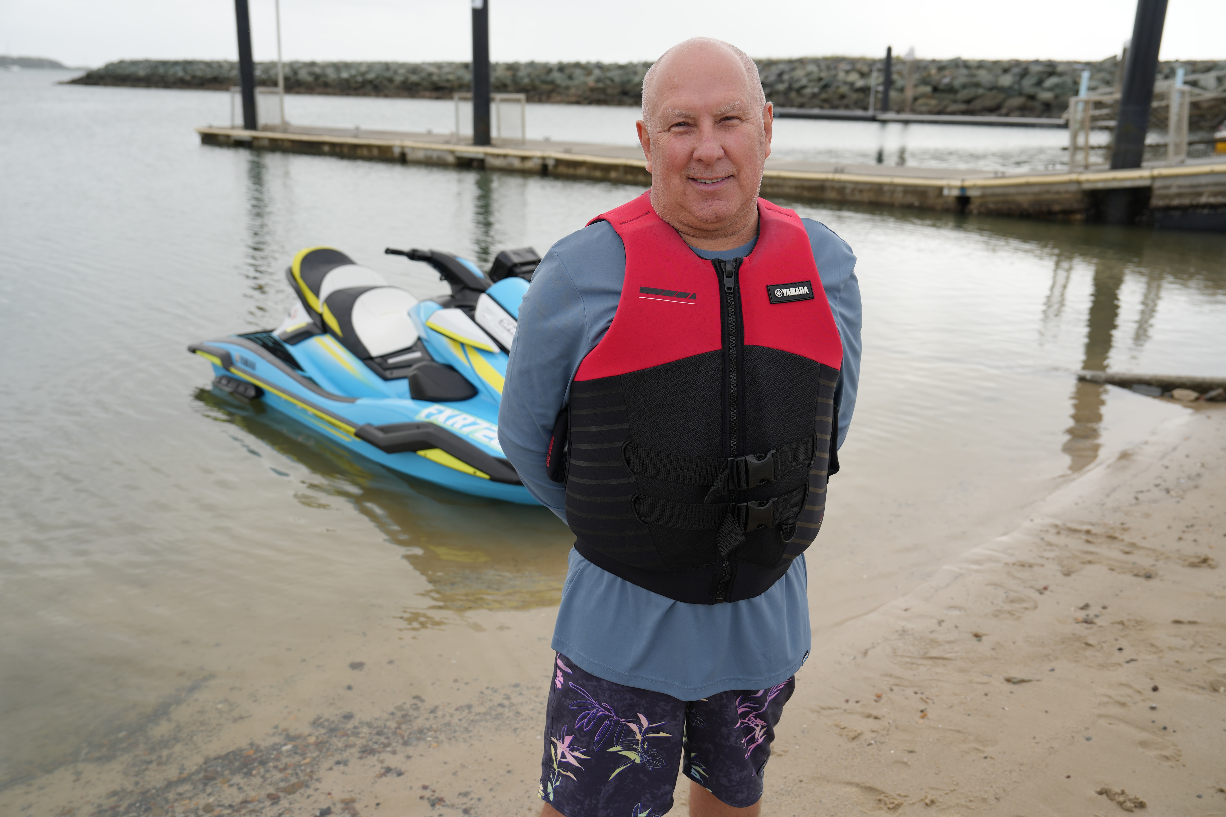 a man in his lifejacket standing in front of a jet ski