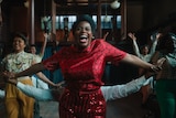 Fantasia as Celie with arms stretched out and a wide smile, dancing with glee, surrounded by others